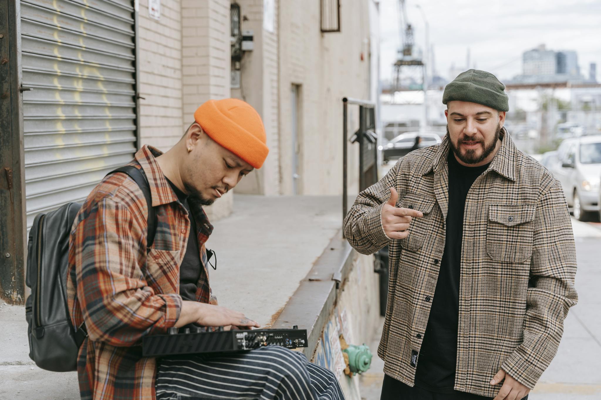 Two men performing music in an urban setting, one playing a keyboard and the other rapping.